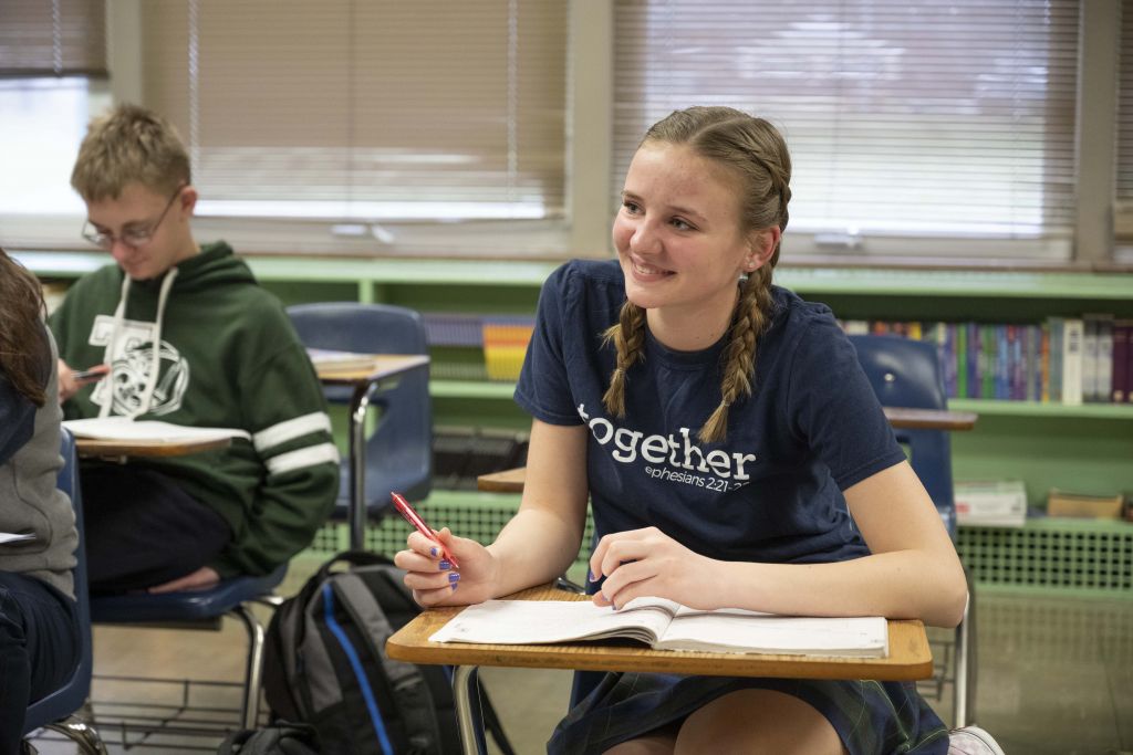 student at desk smiling at teacher