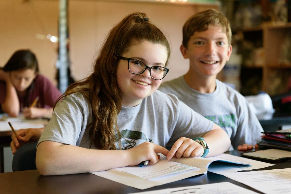 two students sitting at desk smiling