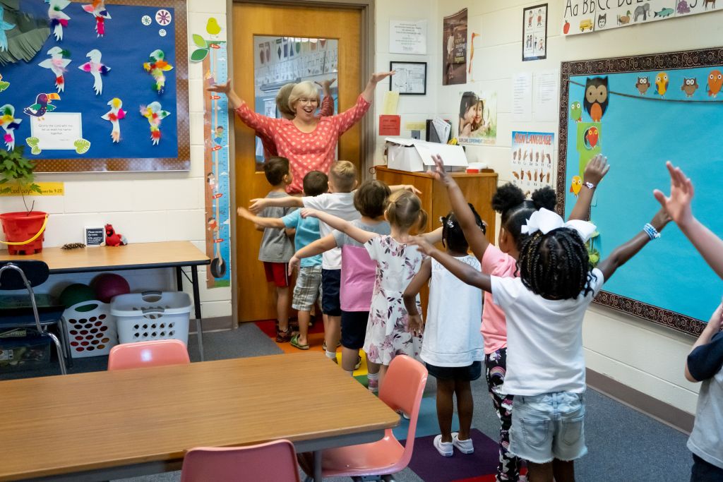 kids lined up in class with arms in air
